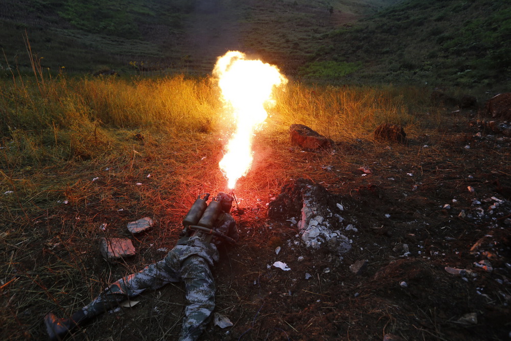 工兵使用喷火枪引燃雷区地表植物,利用高温引爆地雷.