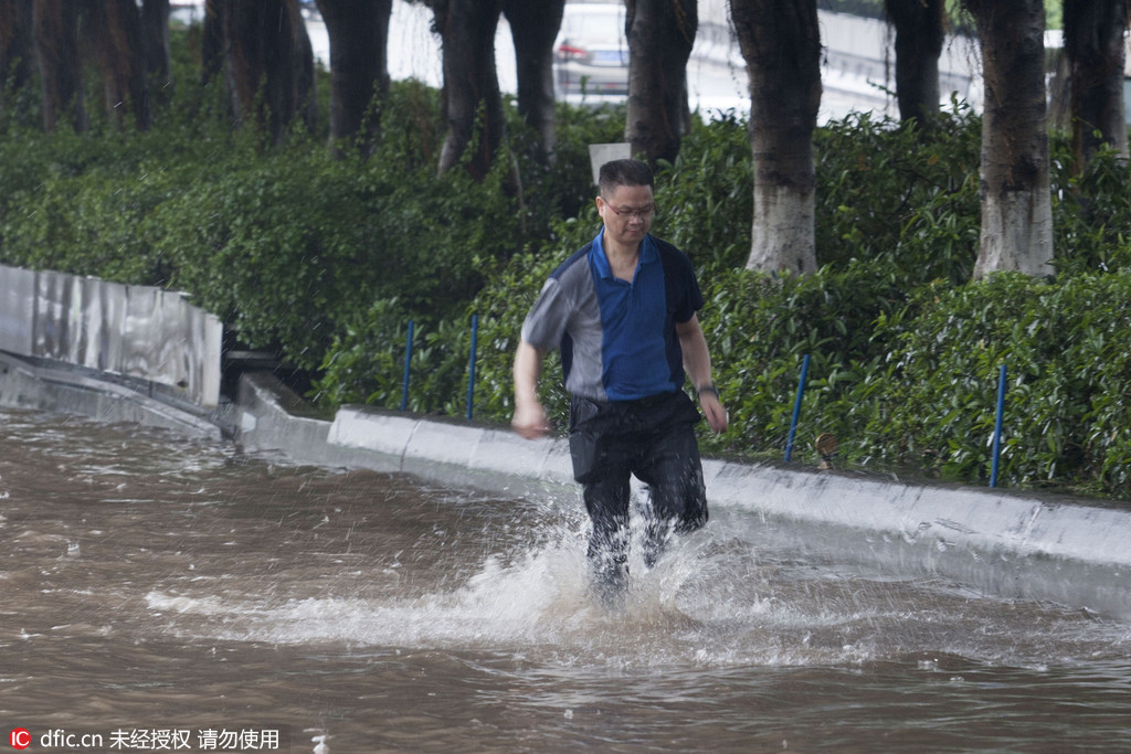 广州遭遇大雨市区多处被淹 市民卷裤管过河