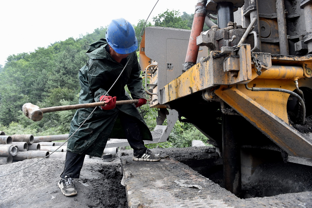 7月5日，在地面2号钻孔，救援人员敲击管道等待井下被困矿工回应。 新华社记者 詹彦 摄