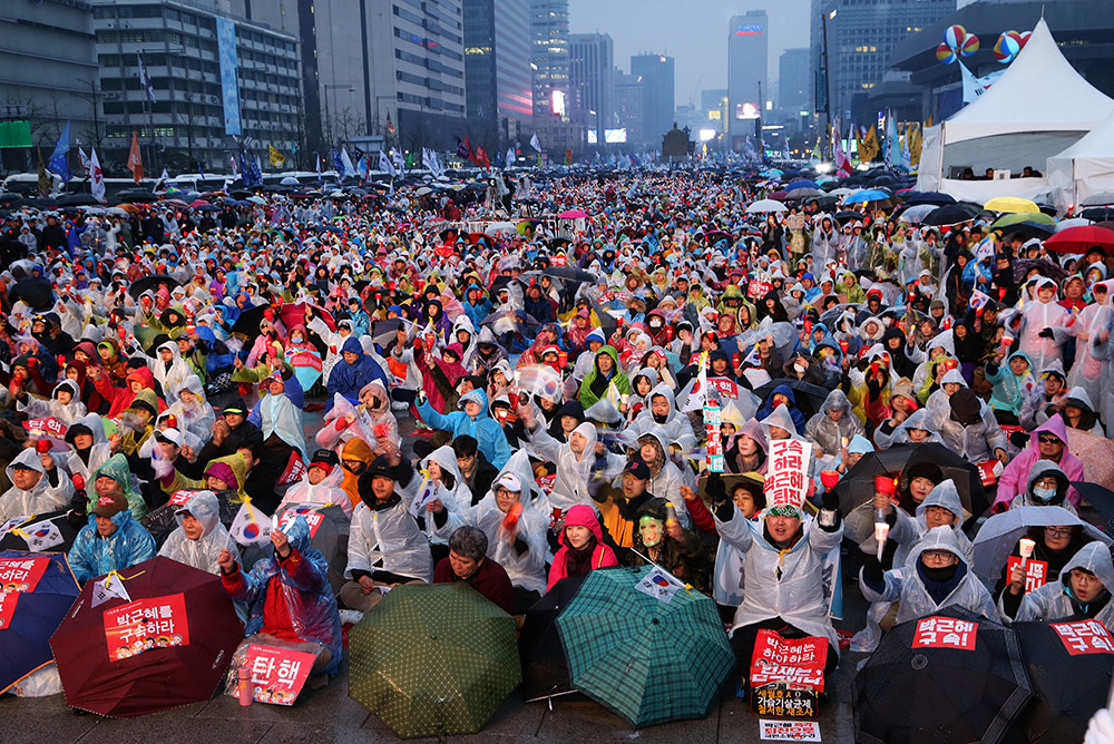 3月1日，在韓國首爾，反對總統朴槿惠的民眾高舉支持彈劾的標語，在雨中參加集會。