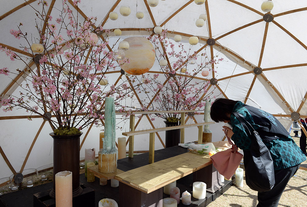 3月11日，在日本東京一處公園設立的紀念場所，一名市民悼念2011年日本大地震和海嘯中的遇難者。