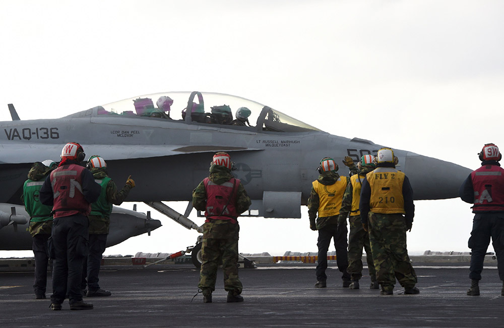 3月14日，在韓國東部海域舉行的韓美聯合軍演期間，“卡爾·文森”號核動力航母上的美國海軍人員站在一架F-18戰斗機旁。