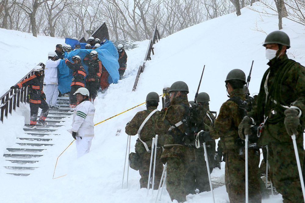 3月27日，在日本栃木縣那須町，搜救人員運送一名雪崩幸存者就醫。新華社/法新