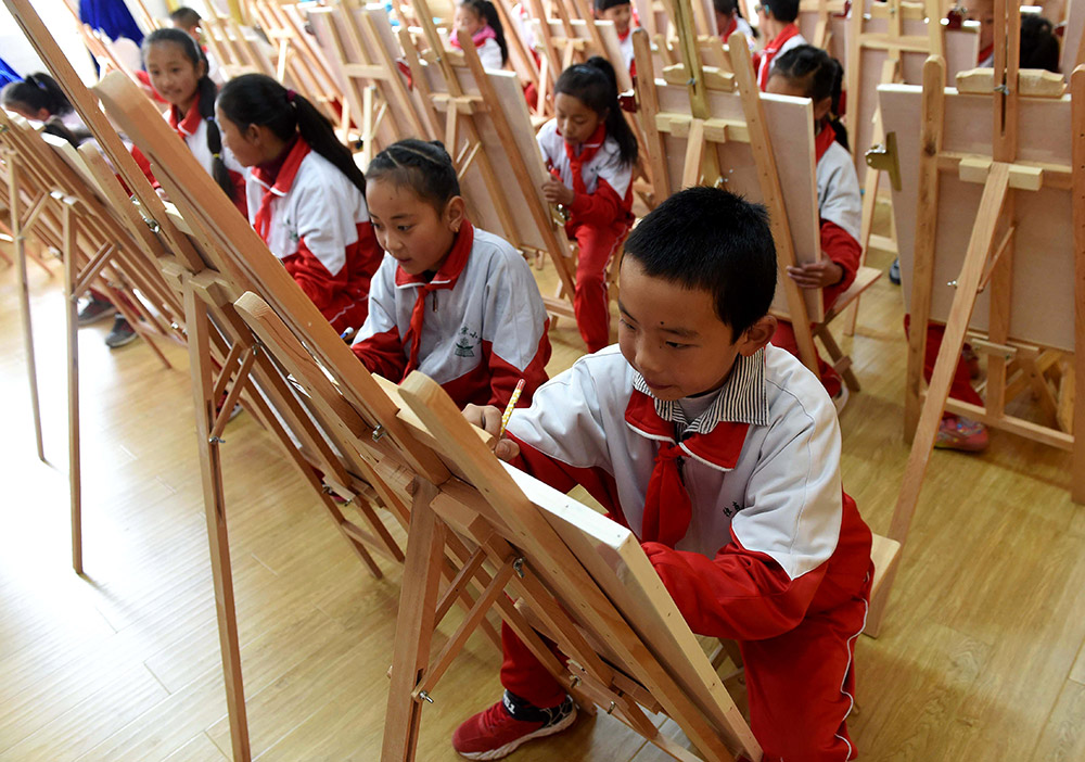 3月27日，獨克宗小學的藏族男孩黃偉（右一）和同學在繪畫興趣班上畫畫。