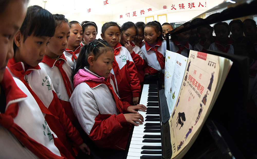 3月27日，獨克宗小學的學生在音樂興趣班上觀看一名藏族同學彈鋼琴。