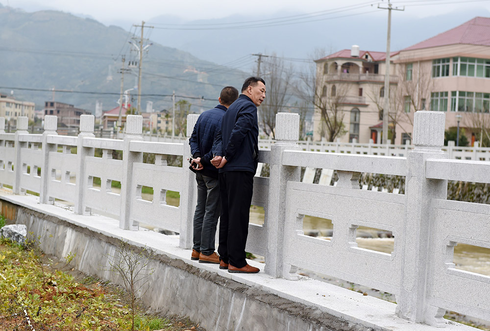 福建省龍岩市小池鎮汪洋村小池溪畔，村主任陳明炯（右）在新修的堤岸上查看河道衛生（3月15日攝）。
