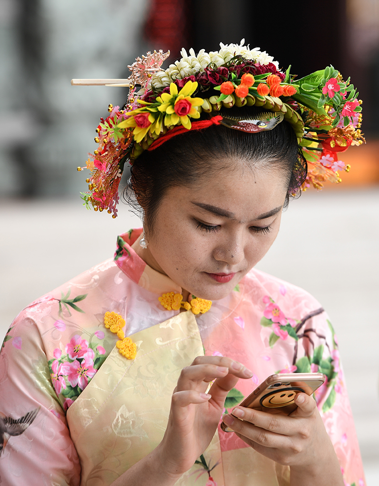 4月9日，在泉州蟳埔村，一名“蟳埔女”在看手機。