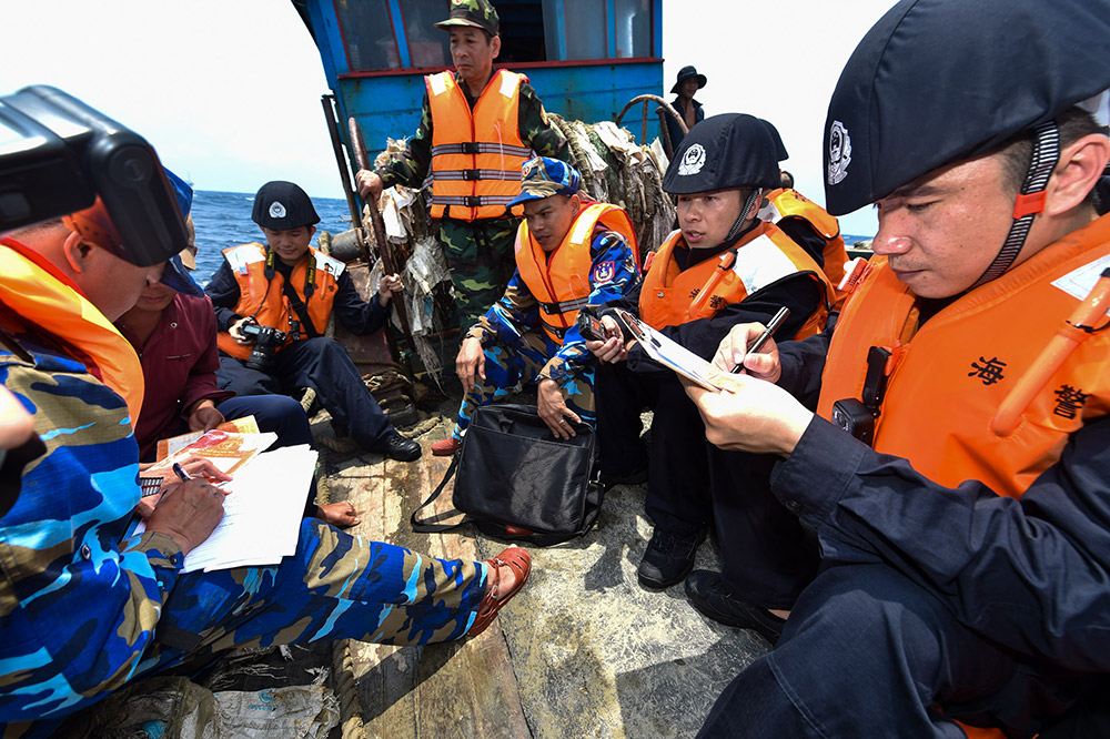 4月18日，在一艘越南漁船上，中國海警（黑衣）和越南海警（藍衣）執法人員詢問並登記船隻信息。