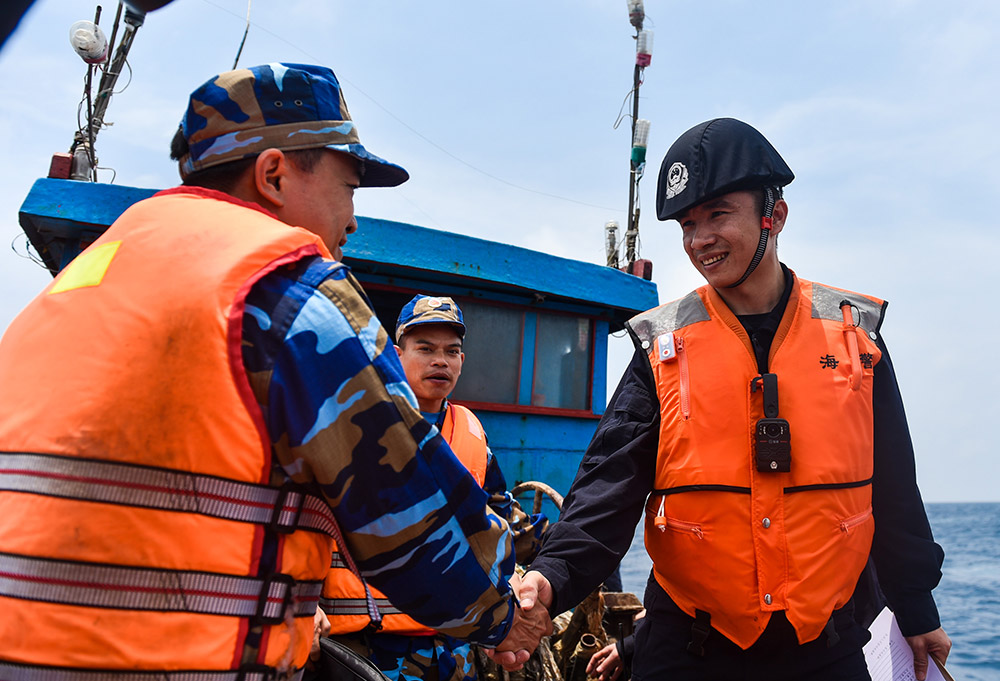 4月18日，在一艘越南漁船上，中國海警（右）和越南海警在聯合檢查前握手致意。