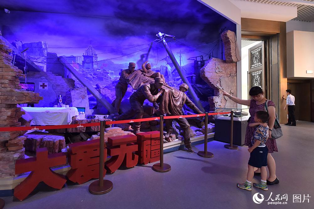 7月24日，在“銘記光輝歷史　開創強軍偉業——慶祝中國人民解放軍建軍90周年主題展覽”上，一位母親正在給兒子講述“汶川地震”時的情景。（人民網記者 翁奇羽 攝）