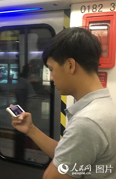 7月30日，在北京地鐵上，乘客正通過手機觀看慶祝中國人民解放軍建軍90周年閱兵直播。（人民網 陳孟 攝）