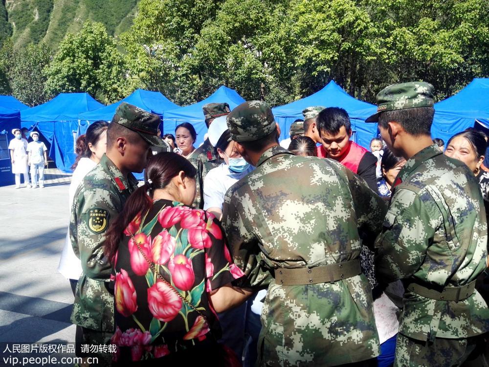 8月9日，武警四川總隊阿壩州支隊九寨溝縣中隊官兵協助醫務人員搬運、轉移傷員前往醫院救治。