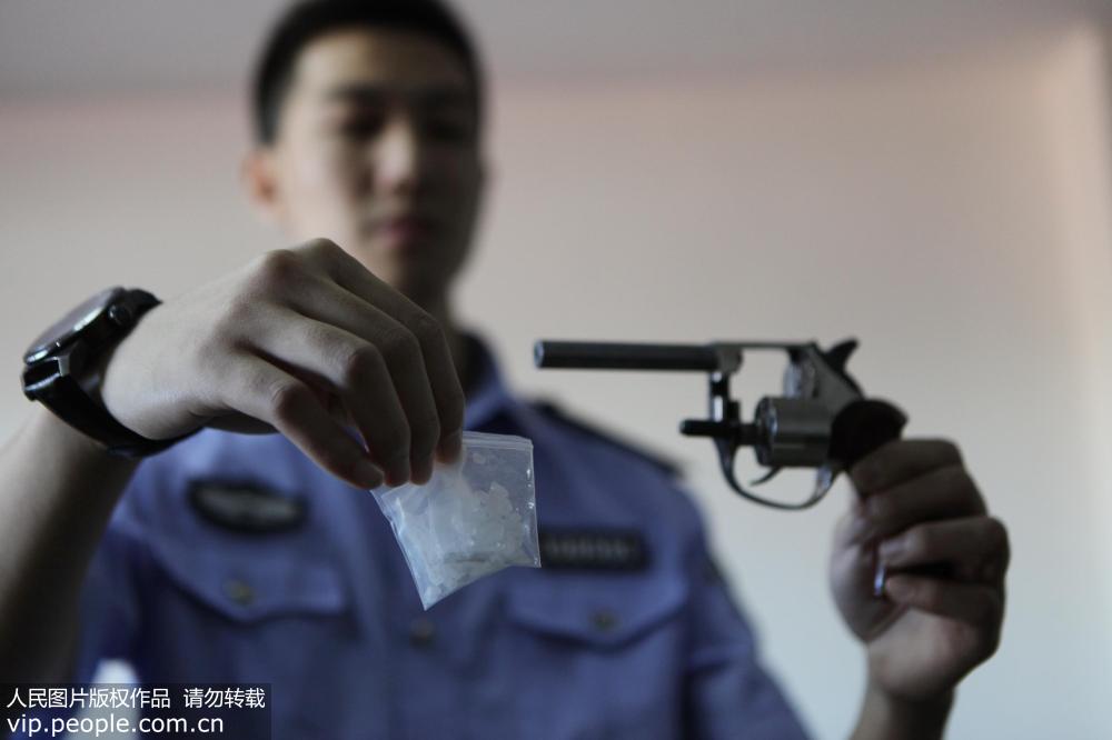 9月19日，沈陽市公安局鐵西分局刑偵禁毒大隊民警正在展示繳獲的毒品及槍支。趙敬東/人民圖片