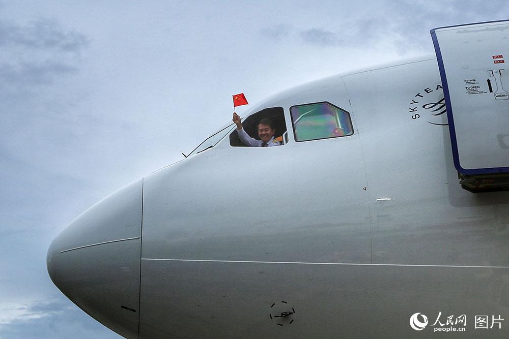東航包機抵達安提瓜和巴布達的維爾·伯德機場，機組人員揮舞著國旗，歡迎同胞回家。（人民網 王初 攝）