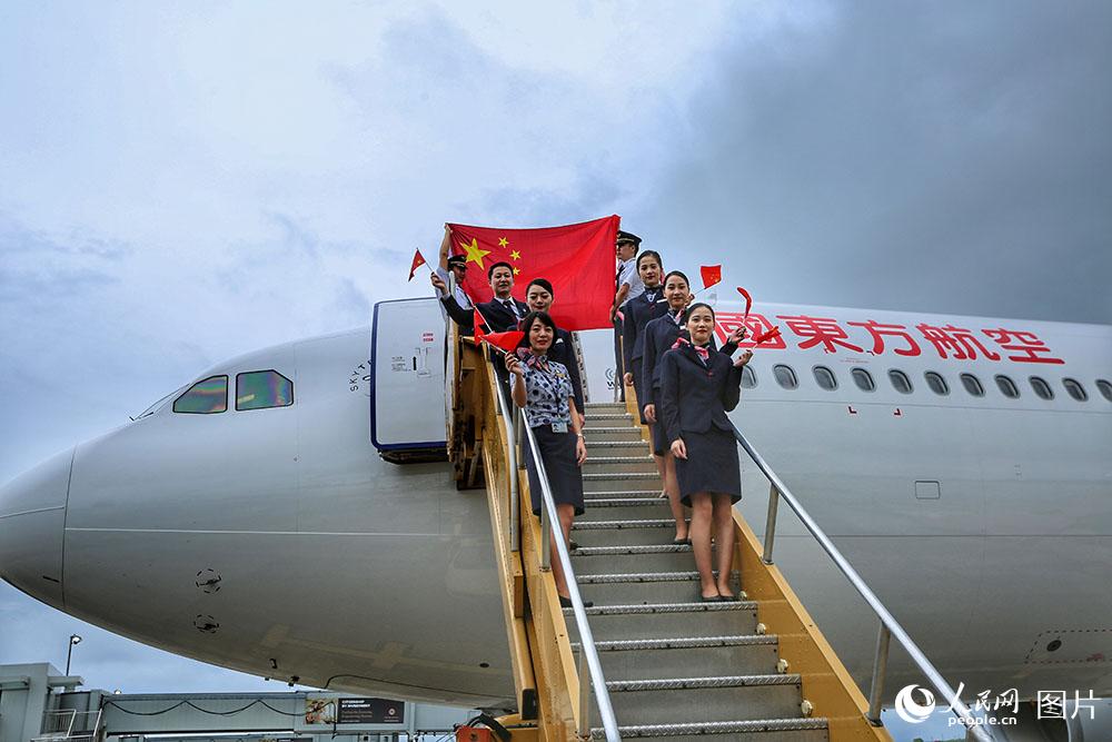東航包機抵達安提瓜和巴布達的維爾·伯德機場，機組人員揮舞著國旗，歡迎同胞回家。（人民網 王初 攝）