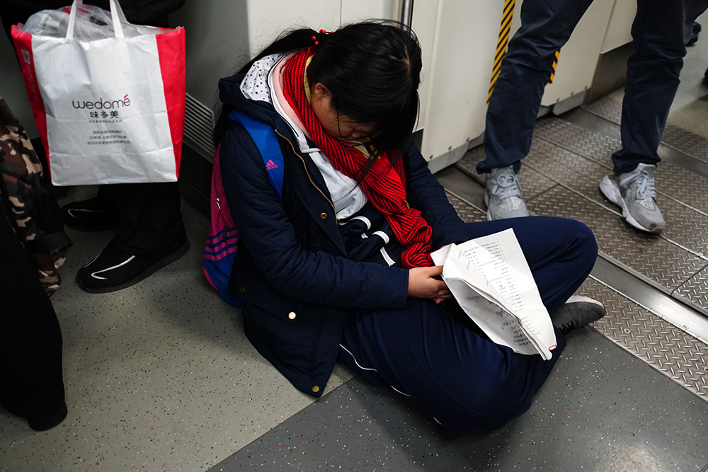 北京:地铁早高峰中学生手握试卷疲惫睡着 乘客