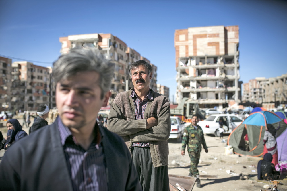 11月13日，在伊朗薩爾波勒扎哈卜，人們站在一處救援地點附近。