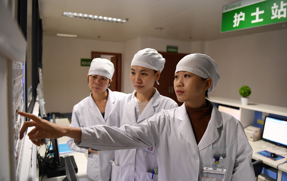 在廣西南寧市第四人民醫院，郭應玲（右一）和同事一起查看病人信息（11月29日攝）。