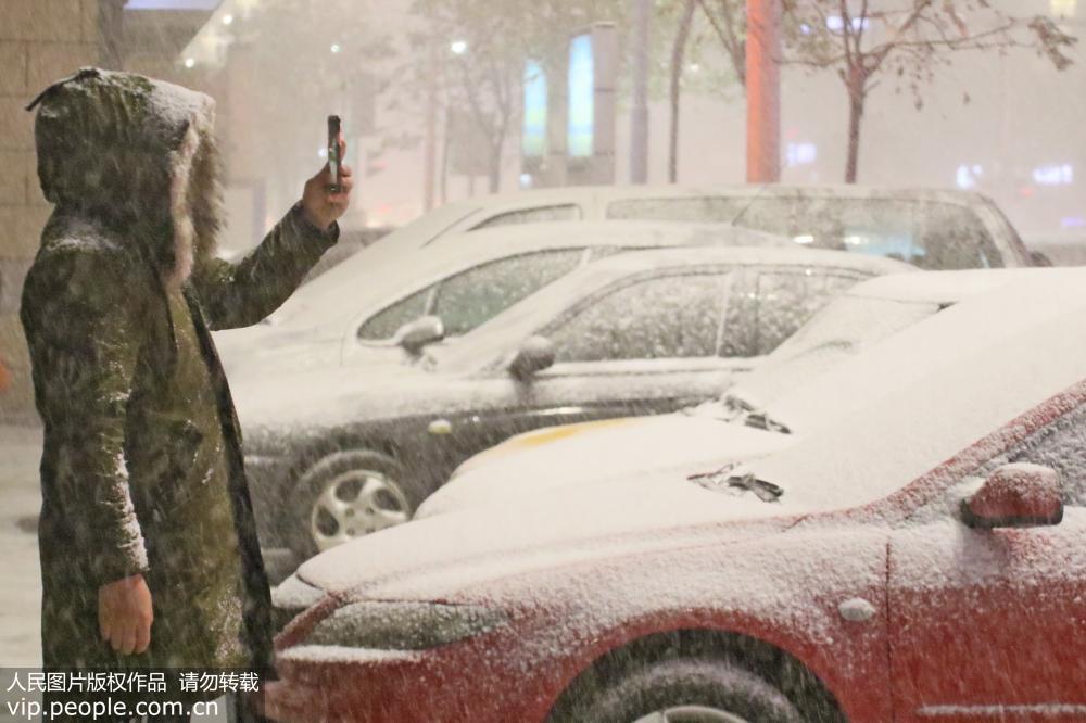 11月30日，在山東省煙台市北馬路，市民在雪中拍照。