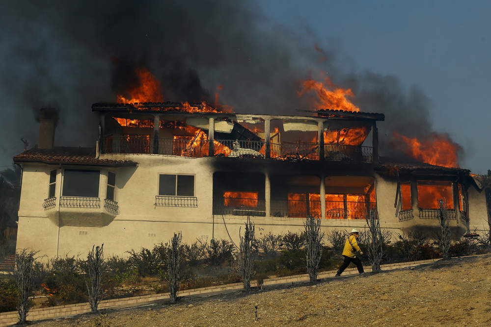 12月5日，在美國加利福尼亞州南部文圖拉縣，消防員經過一處著火房屋。新華社/路透