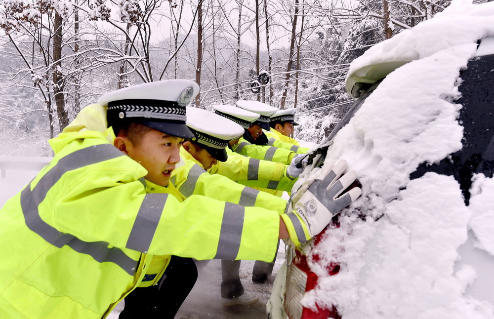 1月4日，在湖北省襄陽市南漳縣，交警在雪中推車。 新華社發（熊明銀 攝）