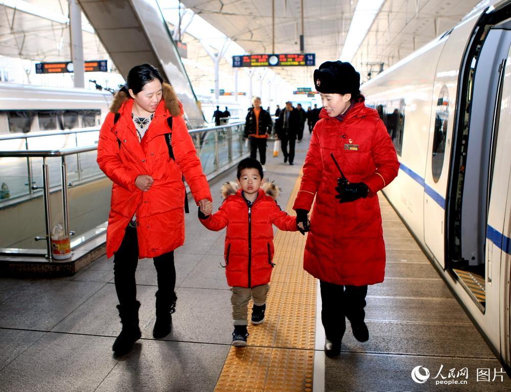 2月7日，天津站365高鐵玫瑰客運員演雲婷（右一）送攜帶兒童旅客登程津京城際列車。