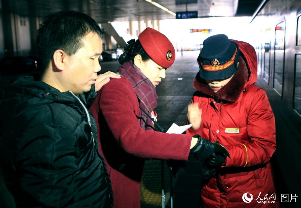 2月7日，天津站365高鐵玫瑰客運員閆雲婷（中）正在向Ｋ２１３次列車乘務員介紹盲人旅客李建紅乘車到站事宜。高錦旭攝