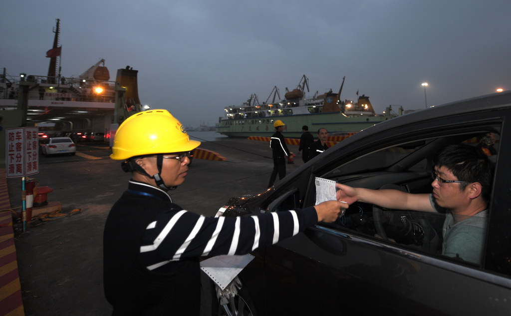 2月25日，在海口市秀英港，一名碼頭工人對通行車輛驗票。 新華社記者 趙穎全 攝