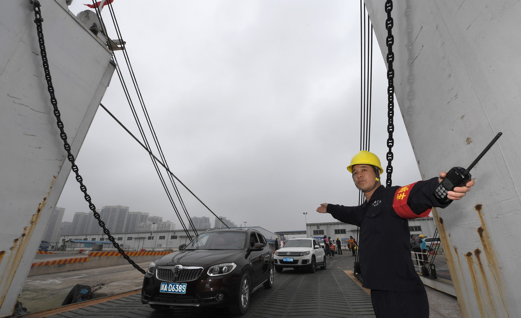2月25日，在海口市秀英港，一名碼頭工人指揮車輛進入渡輪。 新華社記者 趙穎全 攝