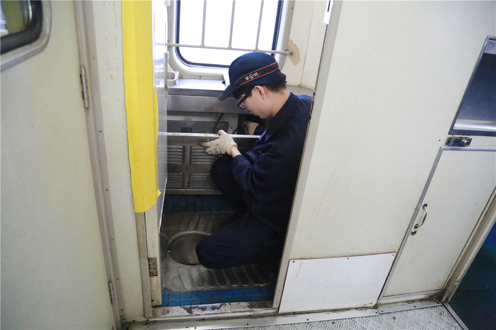 2018年3月5日，重慶車輛段重慶北運用車間廁所革命整治小組成員孫涌檢查K1078次列車集便器控制按鈕。
