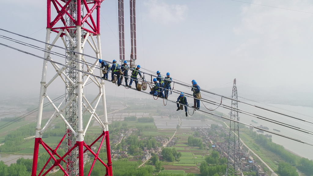 4月15日，在安徽省无为县高沟镇，工人们在昌古特高压长江大跨越工程跨越塔导线上进行高空作业（无人机拍摄）。 新华社记者 郭晨 摄