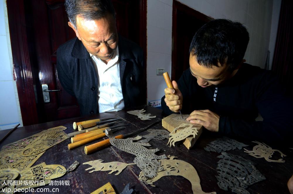 江西省上栗縣綠塘村，69歲的陳開林正在指導陳龍雕刻皮影道具。