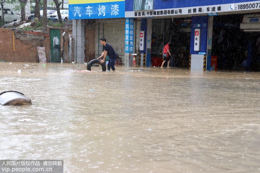 5月7日，在福建省廈門市思明區何厝社，人們在積水中收拾物品。