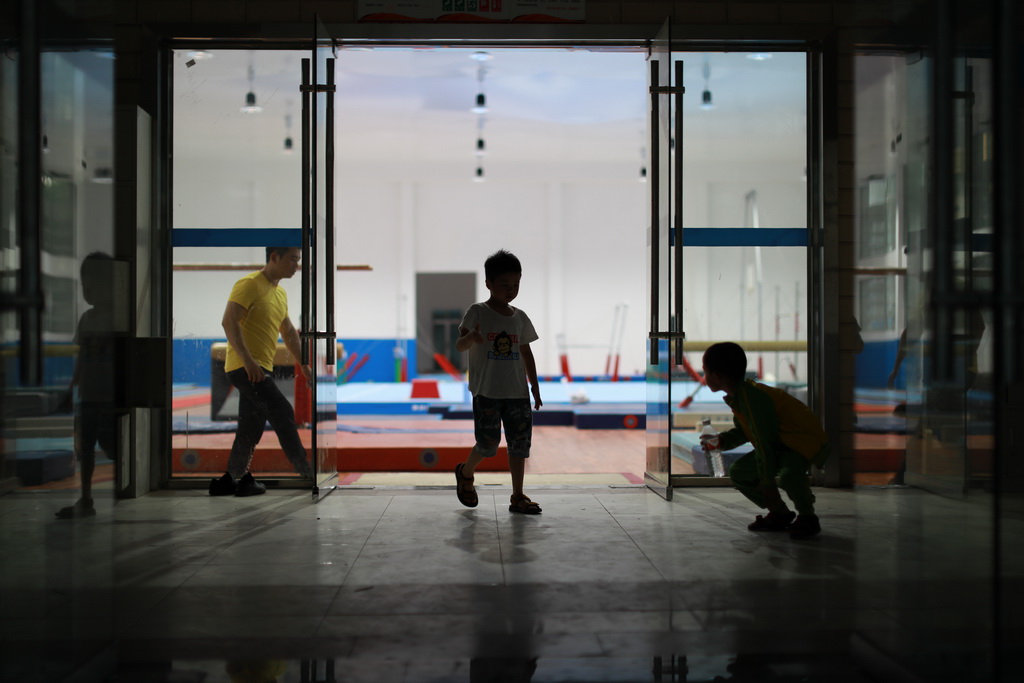 小学员蒋晨晨（中）在结束了一天的训练后走出榕江县少年儿童业余体操运动学校（5月15日摄）。新华社记者刘续摄 