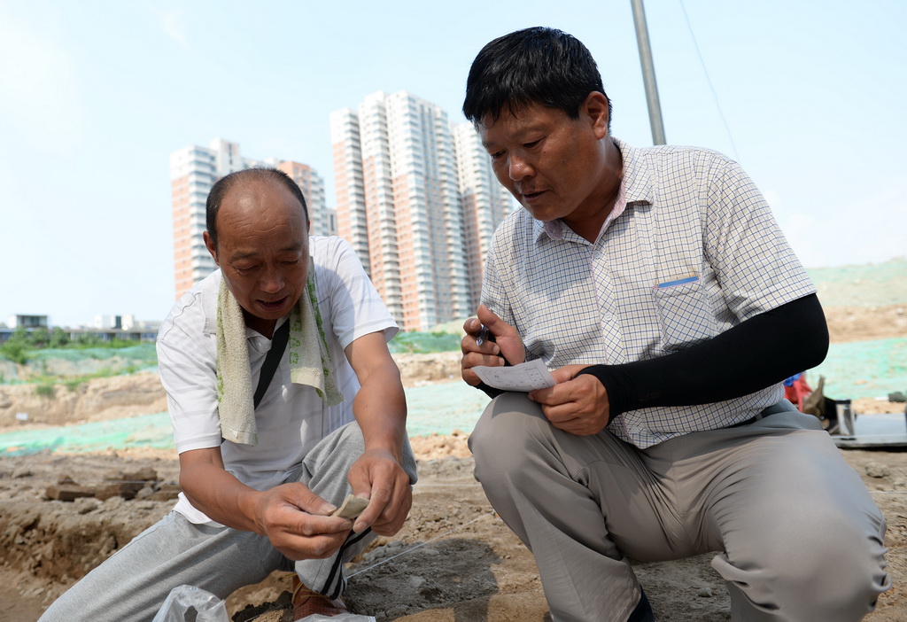 5月15日，考古技師馮小振（右）對西安隋唐長安城東市遺址出土的各類遺物進行登記。  新華社記者 李一博 攝