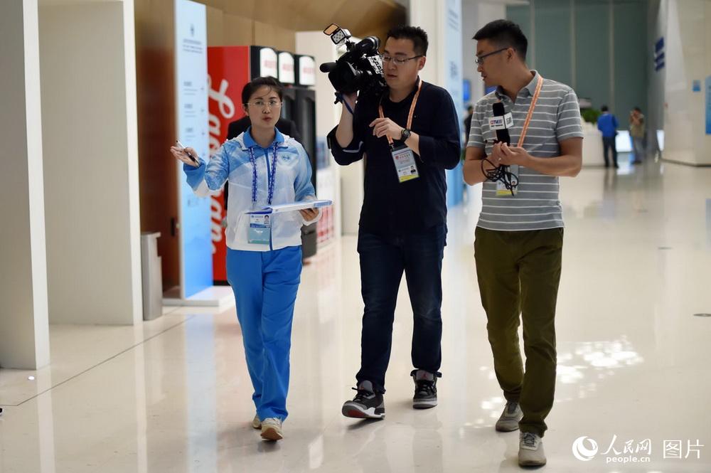 6月7日，中国海洋大学的志愿者曹娟正陪同记者在新闻中心采访拍摄。（人民网记者 翁奇羽 摄）