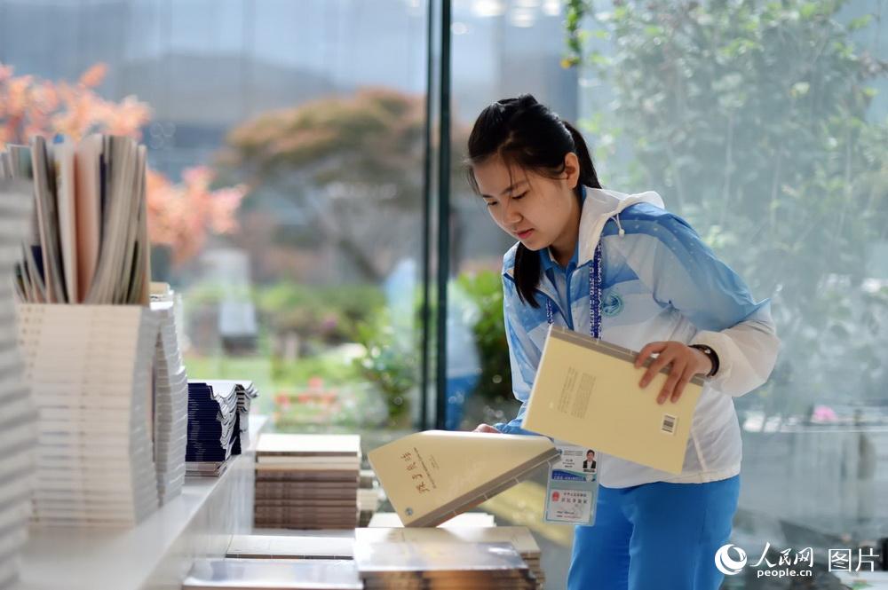 6月7日，来自青岛大学的志愿者任江珊正在整理书架，方便前来采访的记者取阅。（人民网记者 翁奇羽 摄）