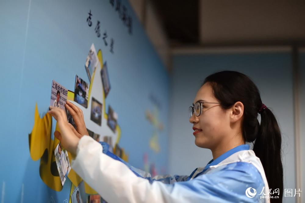 在新闻中心的志愿者之家，来自中国海洋大学的刘晓莉正在布置志愿者风采墙。（人民网记者 翁奇羽 摄）