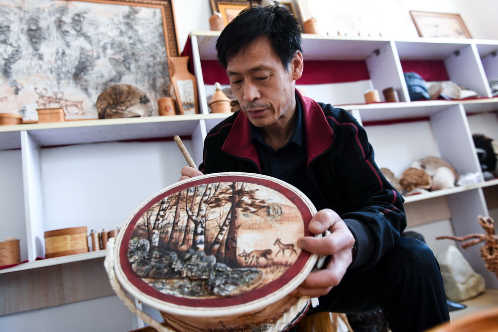 6月7日，在内蒙古自治区根河市的工作室里，王跃辉加工一件带有驯鹿、森林图案的收纳盒。