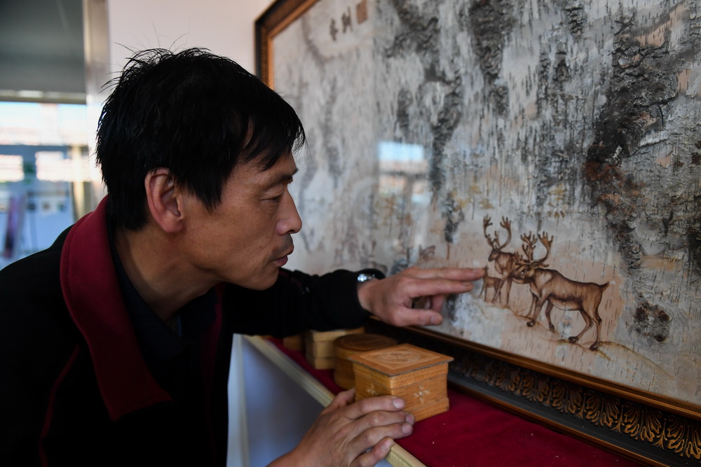6月7日，在内蒙古自治区根河市的工作室里，王跃辉仔细检查一件成品中的驯鹿图案。