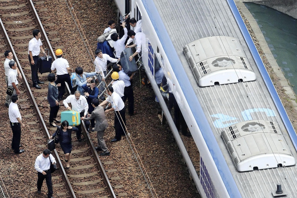 6月18日，在日本大阪，乘客在火車暫停運行后走上鐵道。新華社/美聯