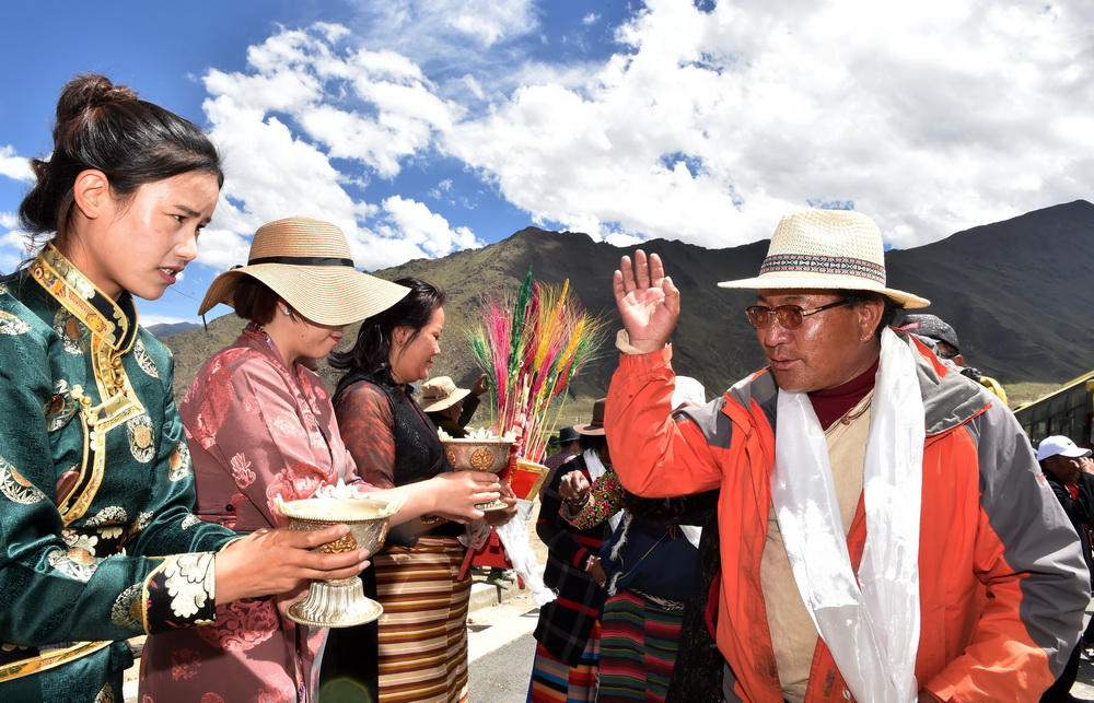 6月18日，嘎沖村群眾（左）向來自遠方的新鄰居敬獻青稞酒。