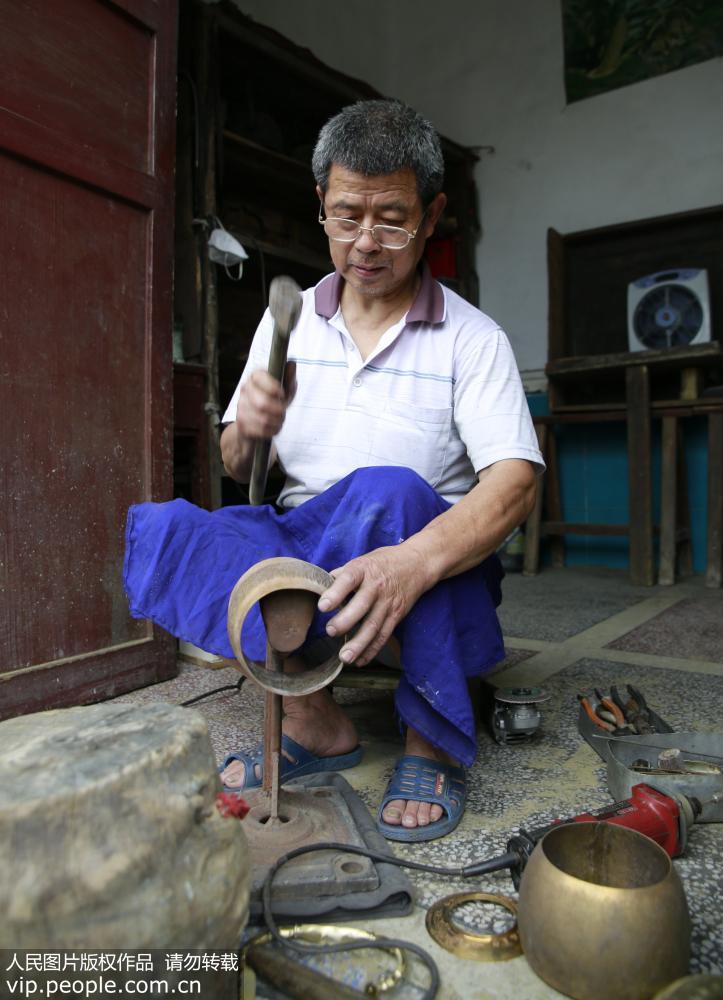 6月19日，民間工匠譚福林對銅壺進行捶型。