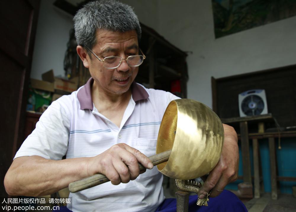 6月19日，民間工匠譚福林對銅壺進行捶型。