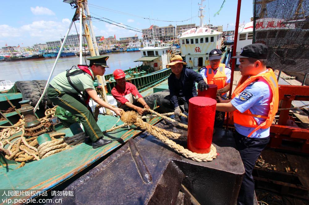 7月10日，浙江省台州市路橋區金清港，公安民警與邊防官兵幫助漁民做好漁船防風加固。