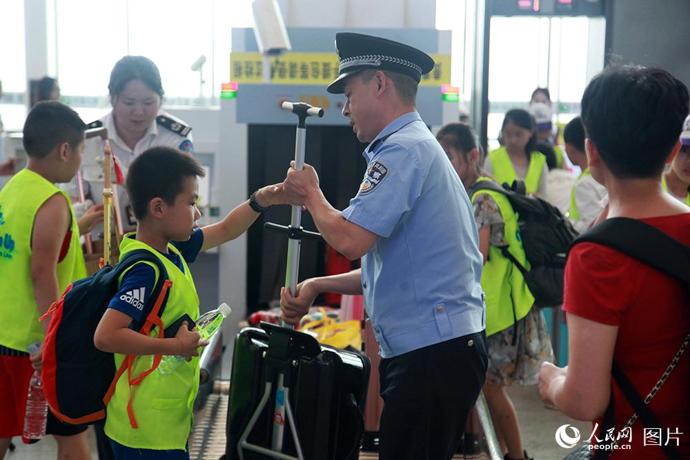 民警在成都東客站安檢口幫助小朋友進站候車。