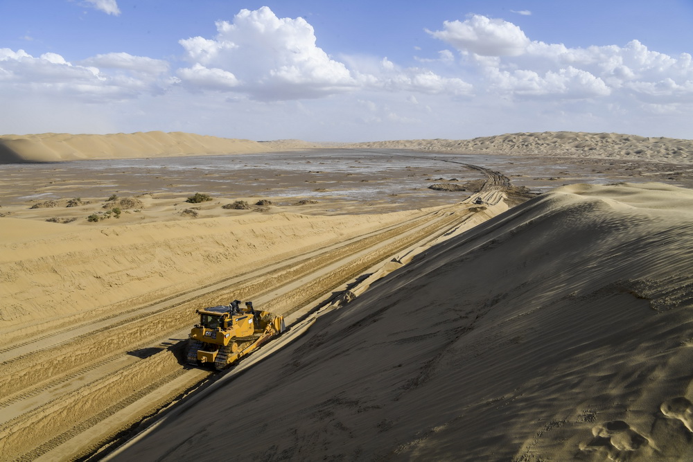 大型推土机在地处塔克拉玛干沙漠深处的施工现场平整沙丘（7月5日摄）。