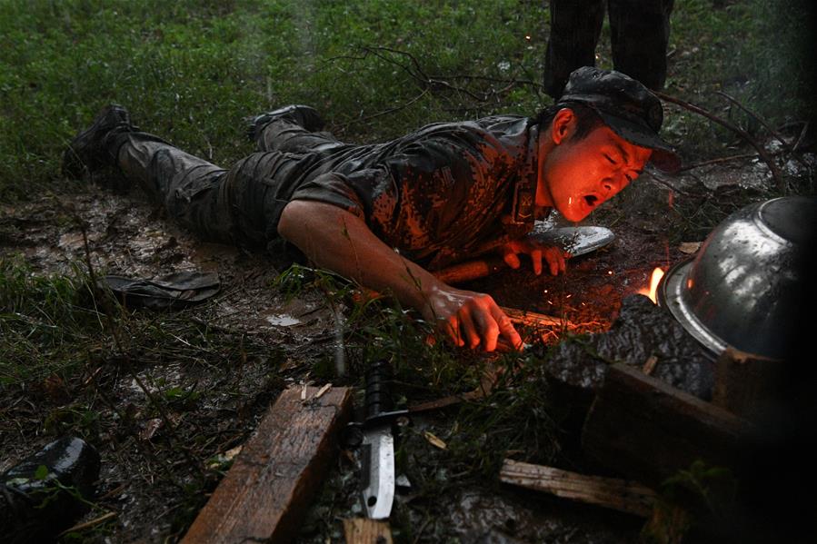 在野战生存课目中，参赛队员在雨中进行钻木取火和冷水煮沸考核（7月16日摄）。 