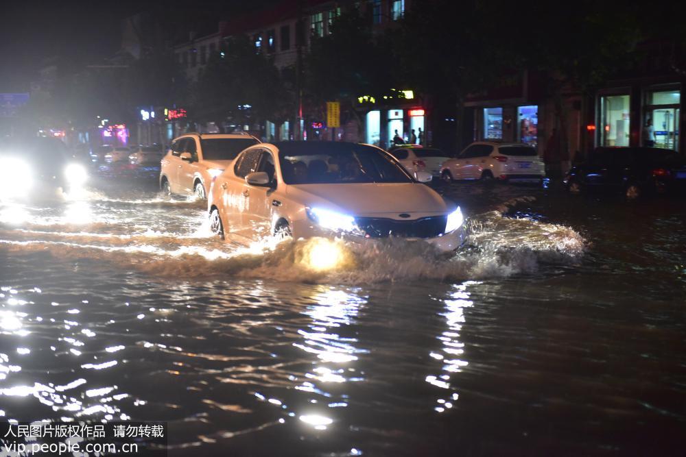 7月18日晚，在河北省石家庄新樂市新華路上，汽車在大水中前行。