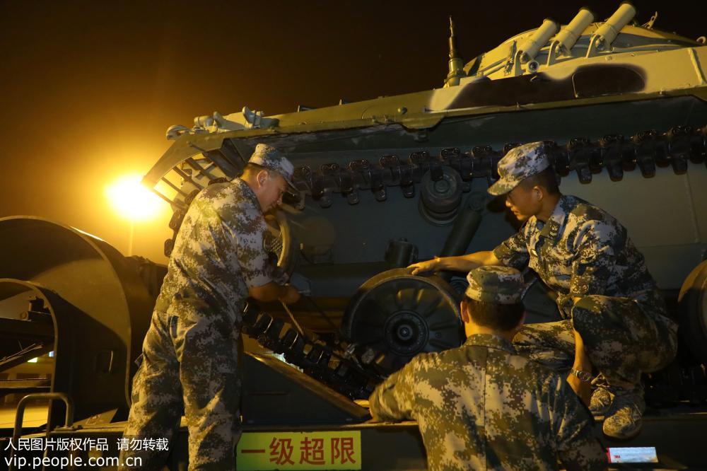 2018年7月19日，迎著夜幕中的燈光中方官兵正在加緊對戰車進行加固。
